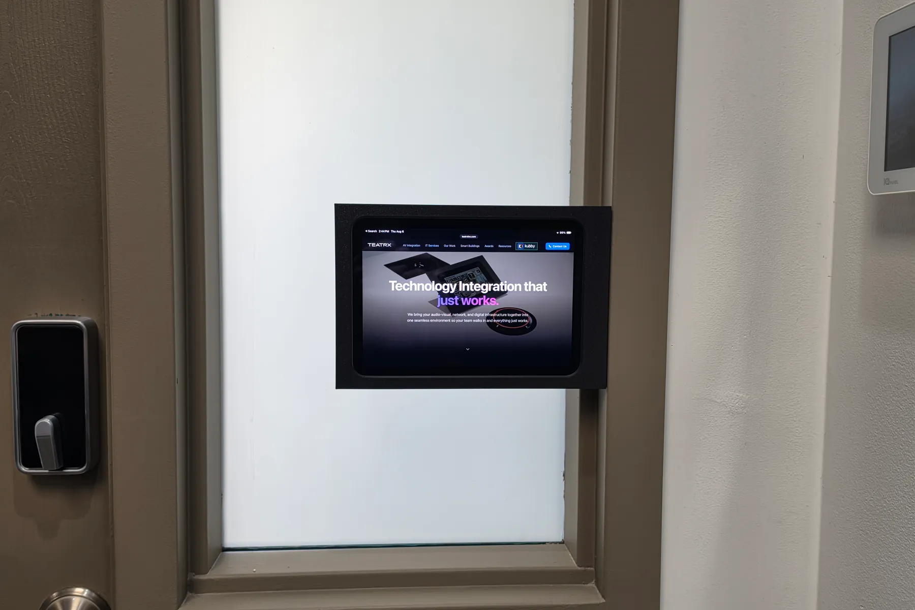 Charcoal iPad Mini Mullion Mount on the glass panel of a door, next to the door lock