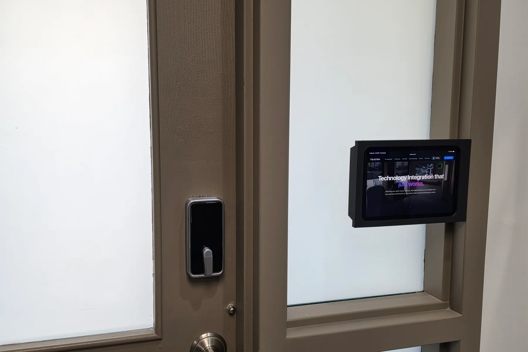 Charcoal iPad Mini Mullion Mount on a glass panel beside a door with a keypad lock