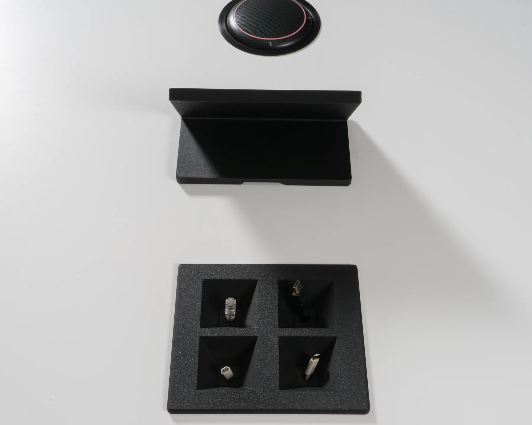 Top-down view of a charcoal Kubby Quatro with four cables, iPad Mini Table Stand and speakerphone behind