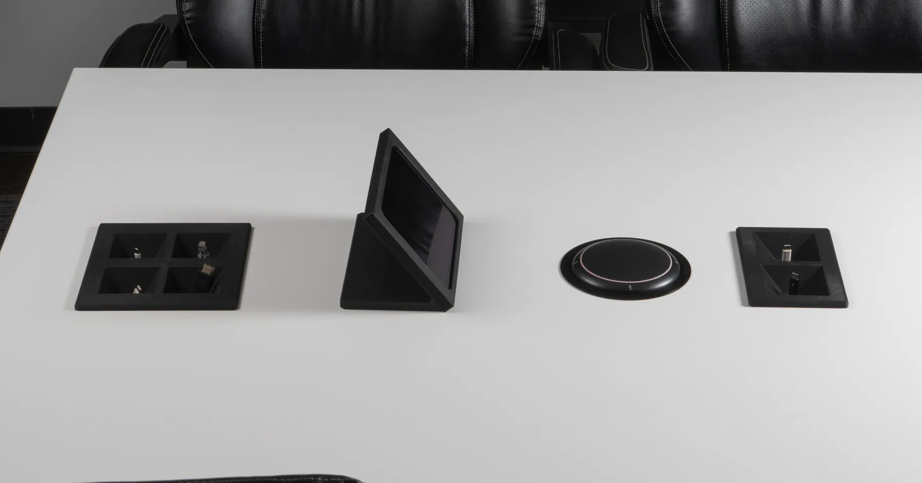 Kubby Quatro, iPad Table Stand and Kubby Dos on a white boardroom table between black leather chairs